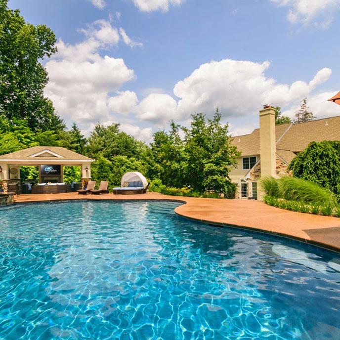 blue pool with outdoor cabana and natural boulder waterfall