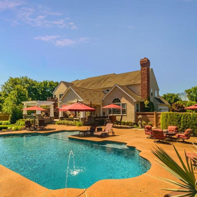 pool area with natural stone fireplace and outdoor dining area with red upholstery and umbrellas