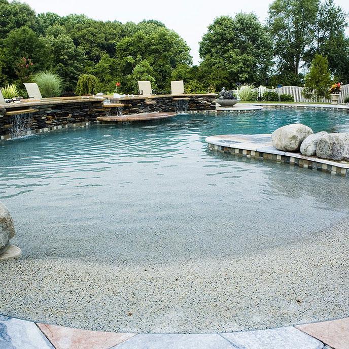 pool with beach-style entry and long, natural stone accent wall