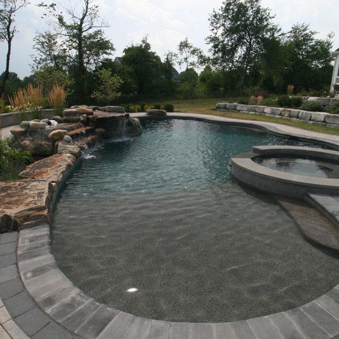 pool with natural setting using boulders, water features and natural stone retaining wall