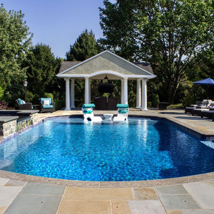 bright blue pool with tanning ledge and pool house