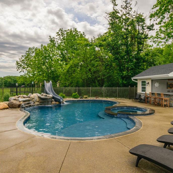 blue pool with waterfall slide and pool house