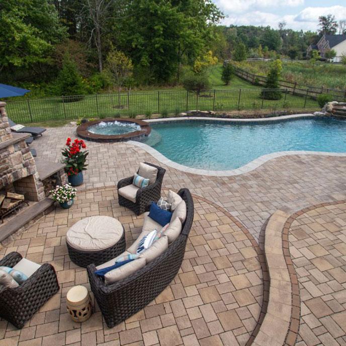 pool area with stone walkway, blue umbrellas enclosed inside a fence