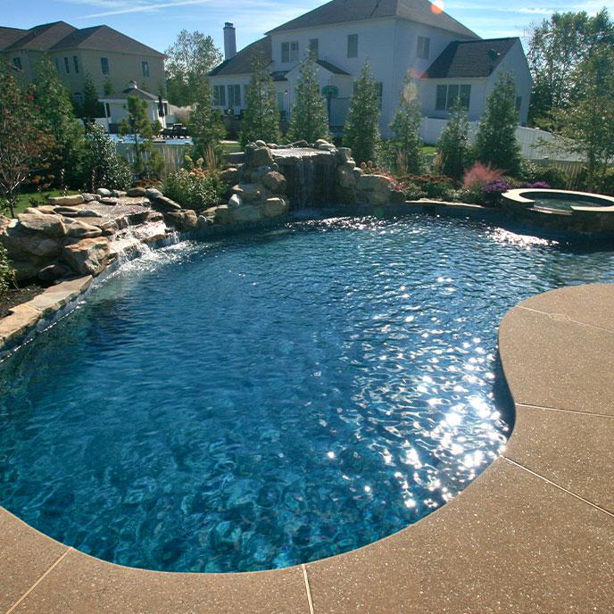 round pool with hot tub and natural rock waterfall