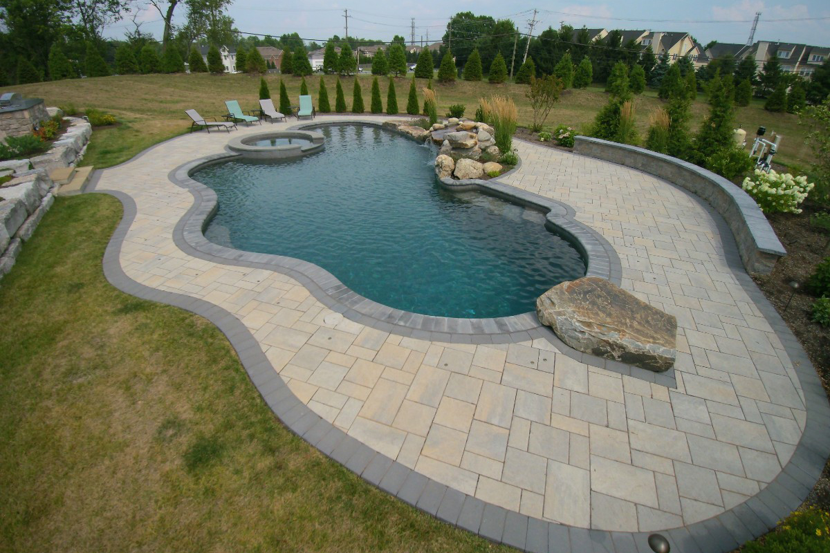 pool with natural setting using boulders, water features and natural stone retaining wall