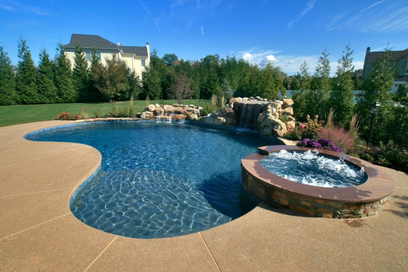 round pool with hot tub and natural rock waterfall